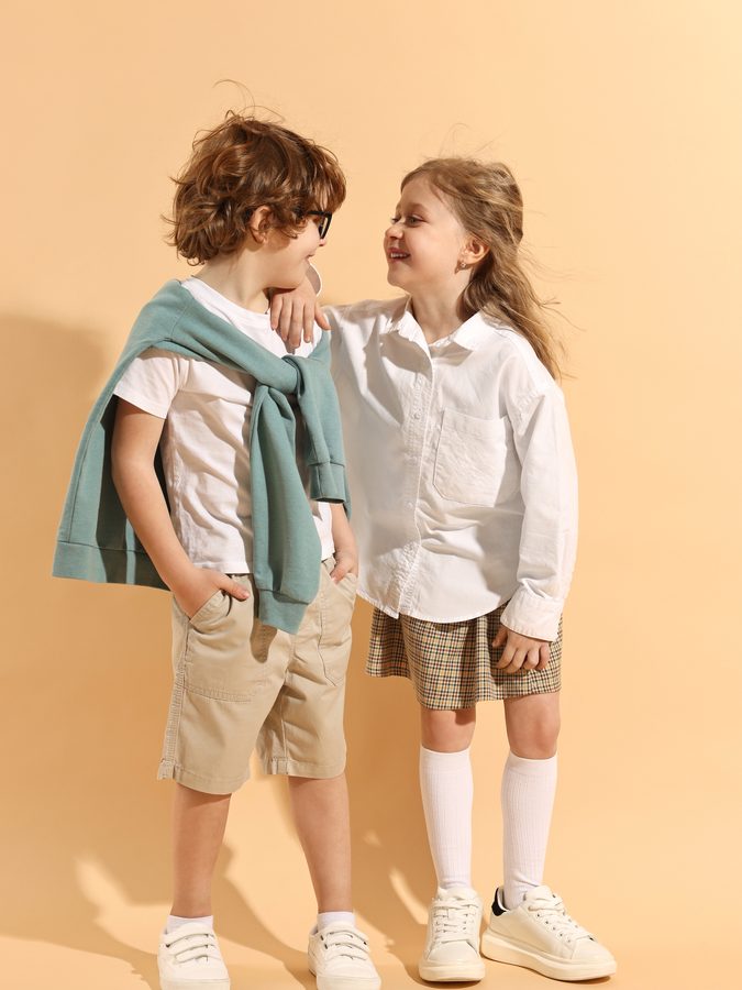 Kidswear — two children in casual coordinated outfits, warm neutral palette