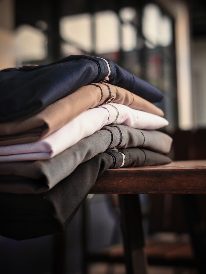 Menswear — folded shirtings and formal fabrics in navy, tan, and cream